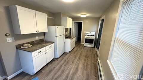 A kitchen with white cabinets and a wooden floor.