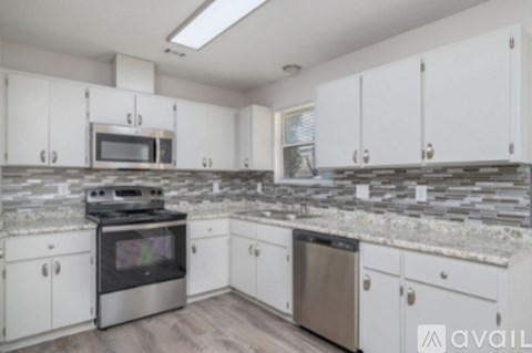 A kitchen with white cabinets and a stone backsplash.
