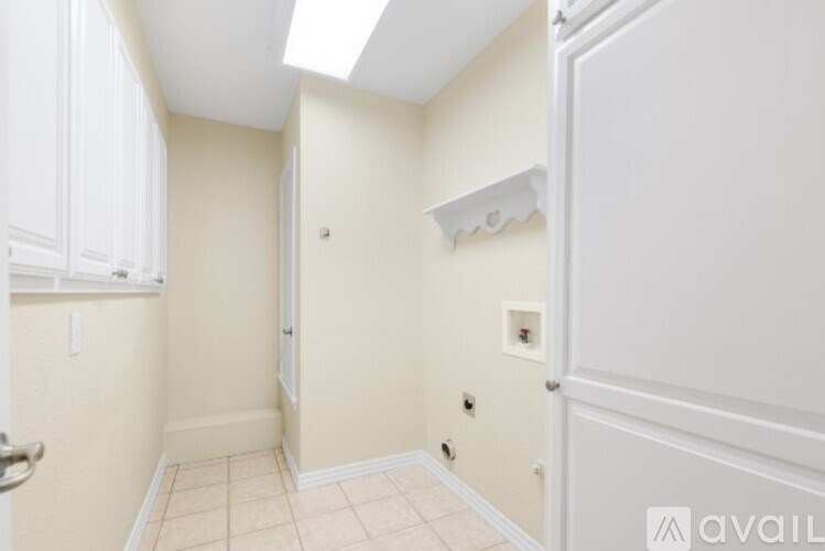 A white door is on the left side of a room with beige walls.