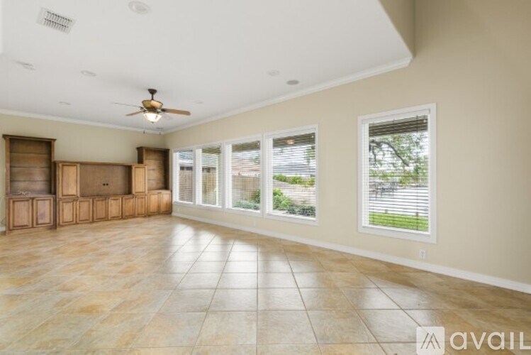 A spacious room with a ceiling fan and large windows.