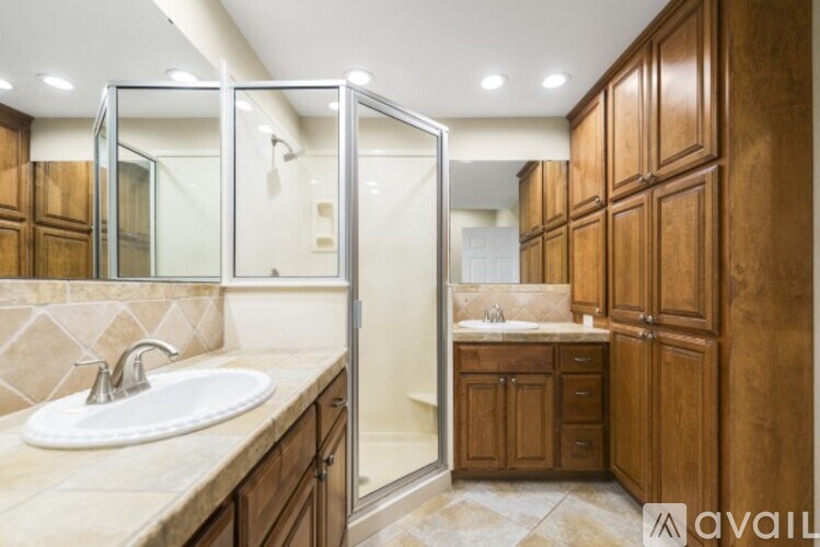 A bathroom with a sink, mirror, and wooden cabinets.