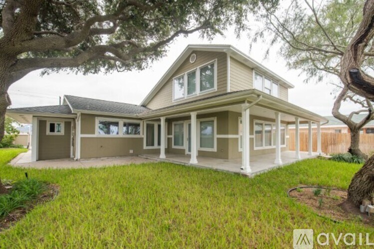 A house with a large front yard and a tree in the foreground.