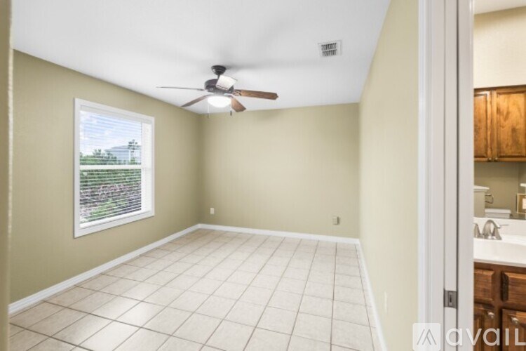 A room with a ceiling fan and a window overlooking a garden.