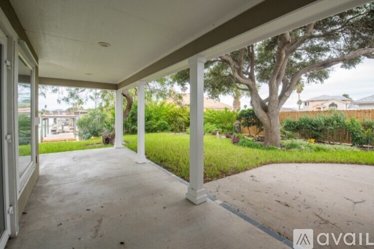 A patio with a white railing and a tree in the background.