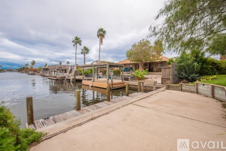 A dock with a house and palm trees in the background.