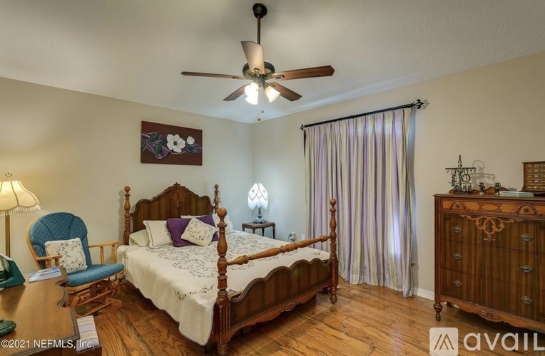 A bedroom with a bed, chair, and a ceiling fan.