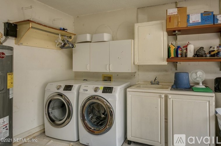 A laundry room with two washing machines and a cabinet.
