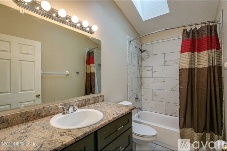 A bathroom with a marble countertop and a white sink.