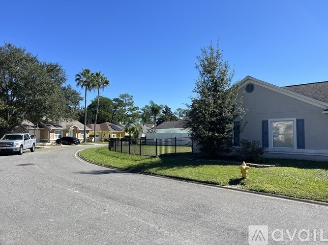 A residential street with houses and cars parked on the side.