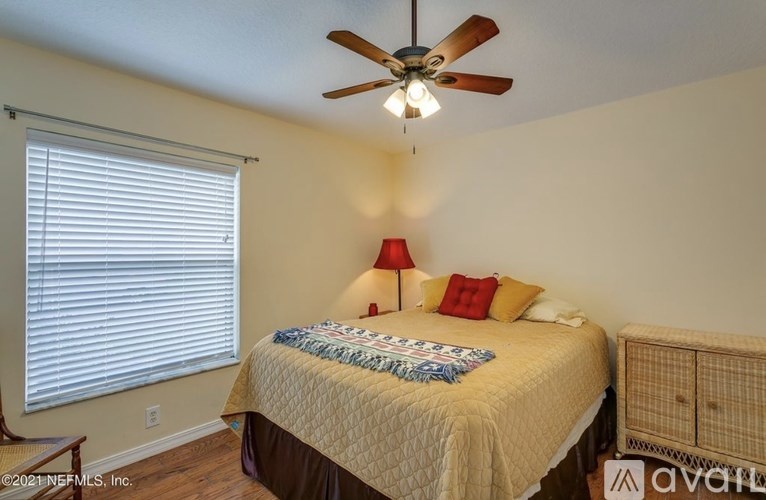 A bedroom with a bed, a ceiling fan, and a window with blinds.