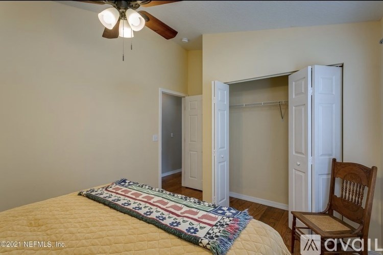 A bedroom with a bed, chair, and a ceiling fan.