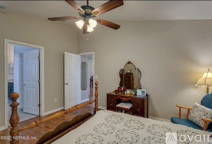 A bedroom with a bed, a chair, and a mirror.