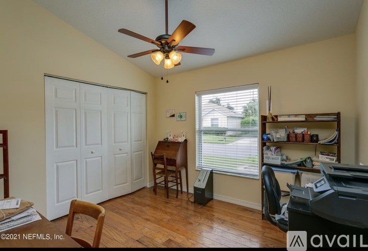A room with a ceiling fan and a desk with a computer.