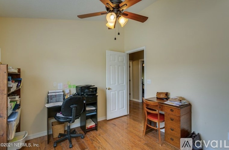 A room with a ceiling fan and a desk with a chair.