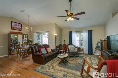 A living room with a brown leather couch and a ceiling fan.