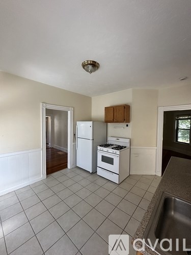 A kitchen with white appliances and a tiled floor.