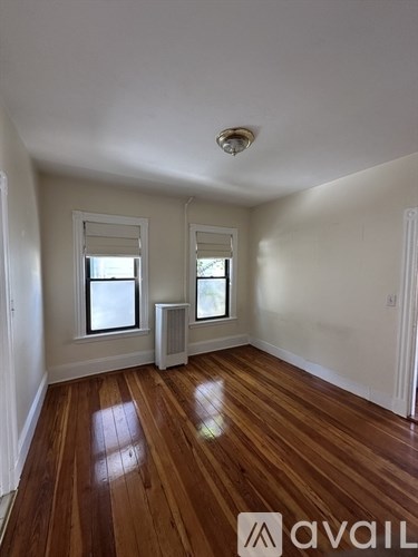 A room with wooden floors and two windows.