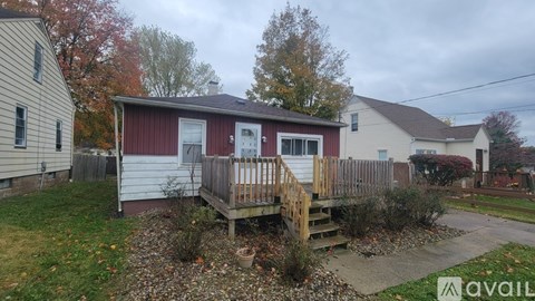 A small house with a red and white exterior is surrounded by a wooden fence and has a small garden in front.