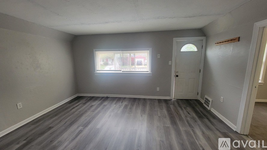A room with a grey floor and a window letting in sunlight.