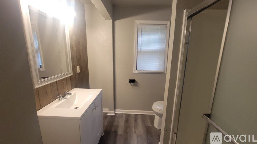 A bathroom with a sink, toilet, and a window.