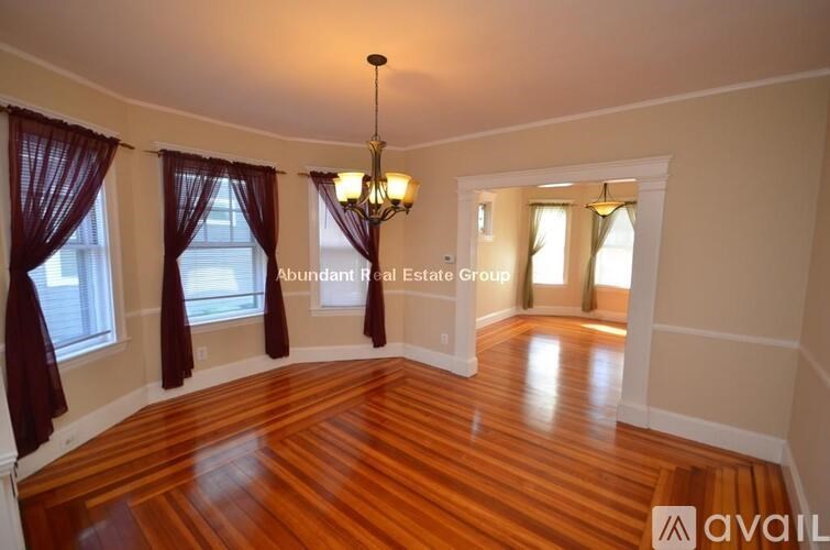 A room with wooden floors and a chandelier hanging from the ceiling.