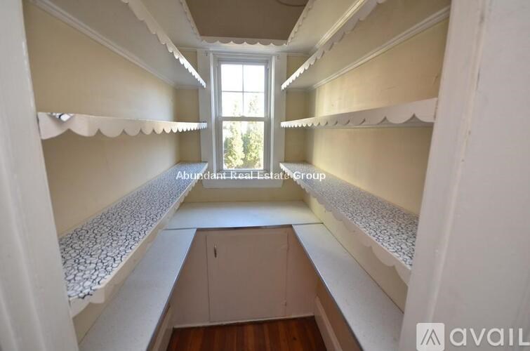 A long, narrow room with a window and a cabinet in the middle.