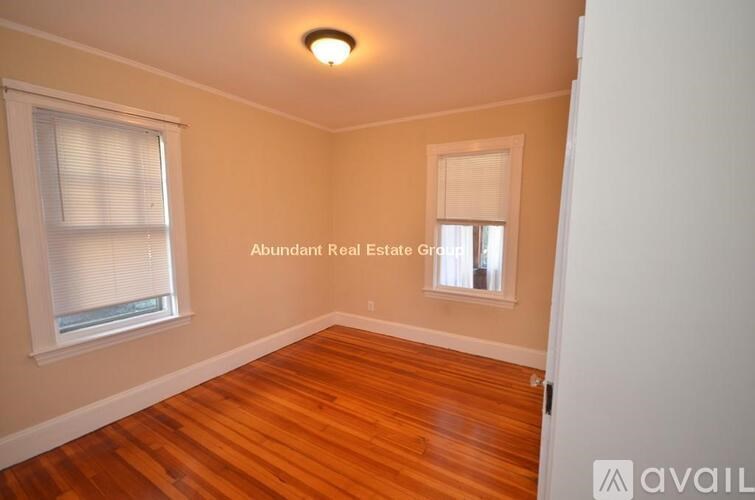 A room with wooden floors and a window with blinds.