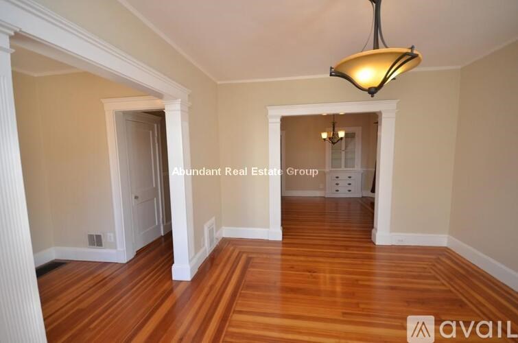 A hallway with wood floors and a chandelier hanging from the ceiling.