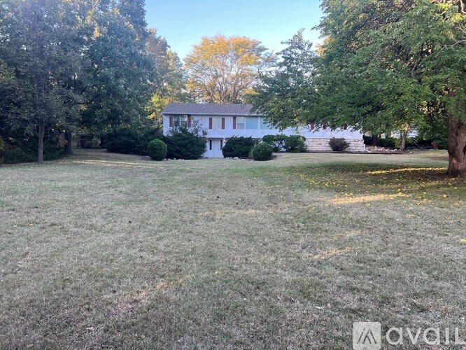 A white house is surrounded by trees and grass.