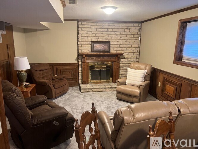 A living room with a fireplace and leather chairs.