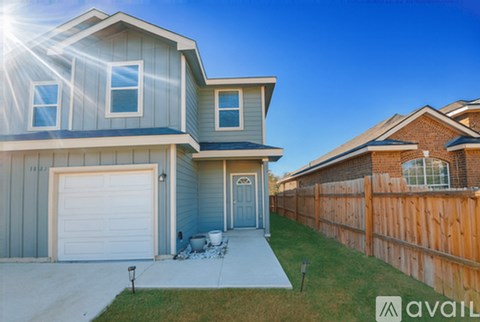 A house with a garage and a fence in front of it.