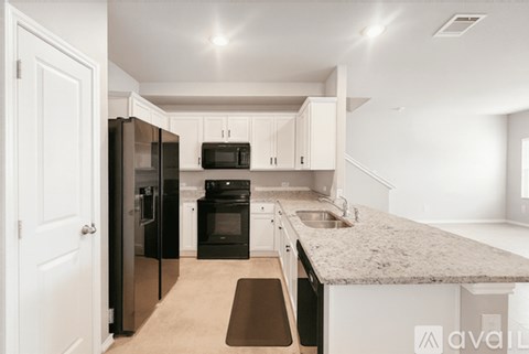 A kitchen with black appliances and white cabinets.
