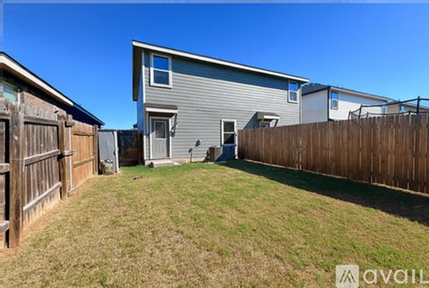 A backyard with a wooden fence and a house in the background.