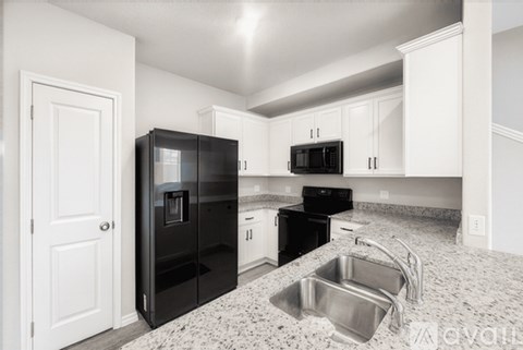 A kitchen with black appliances and white cabinets.