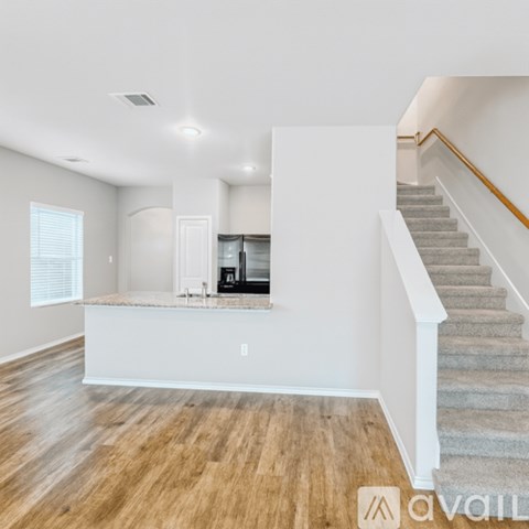A spacious living room with a staircase leading to the upper floor.