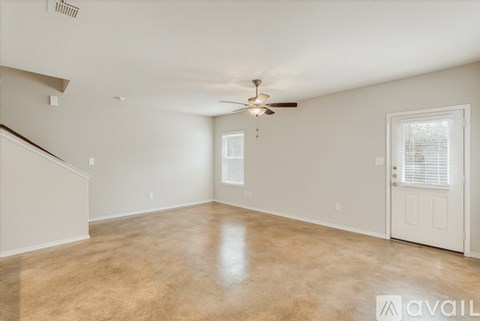 A spacious room with a ceiling fan and a door leading to another room.