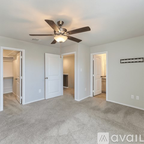 A room with a ceiling fan and three doors.