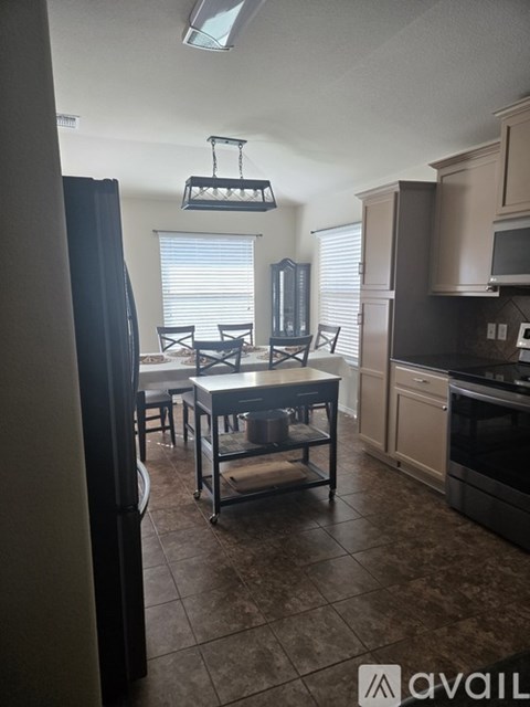 A kitchen with brown tile flooring and a table set for four.