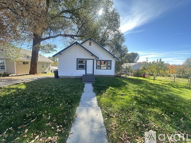 A small white house with a tree in front of it.