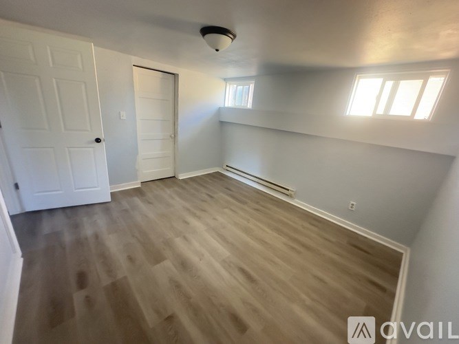 A room with light wood flooring and white walls.