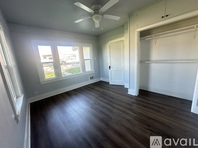 A room with a ceiling fan and a large window.