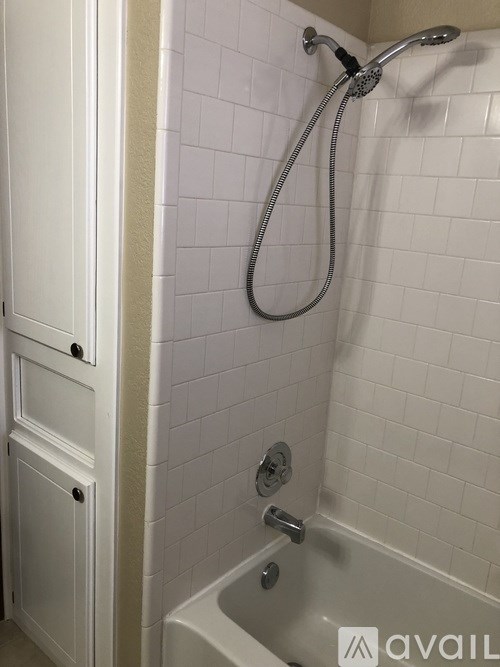 A white tiled bathroom with a white tub and a white shower door.