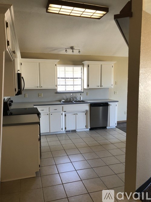 A kitchen with white cabinets and a black countertop.