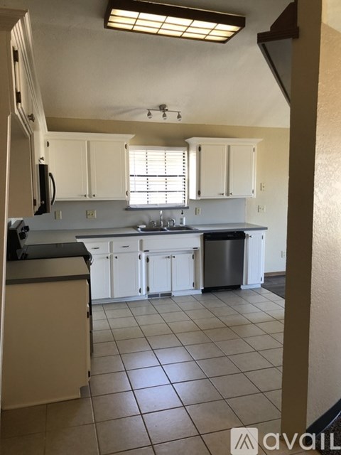 A kitchen with white cabinets and a black countertop.