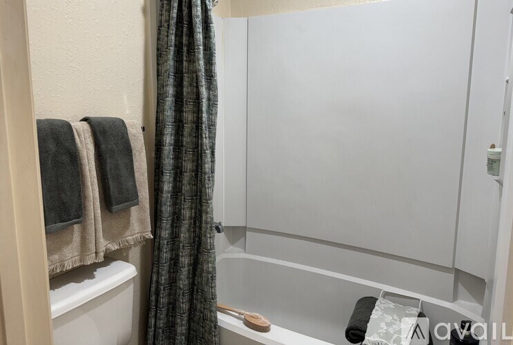 A bathroom with a white tub and a grey shower curtain.