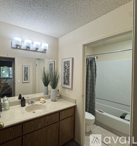 A bathroom with a sink, mirror, toilet, and a bathtub.