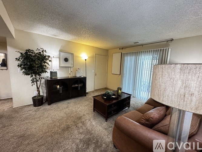 A living room with a brown couch, a wooden coffee table, and a plant.