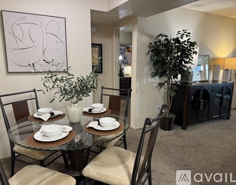 A dining room with a glass table set for four.