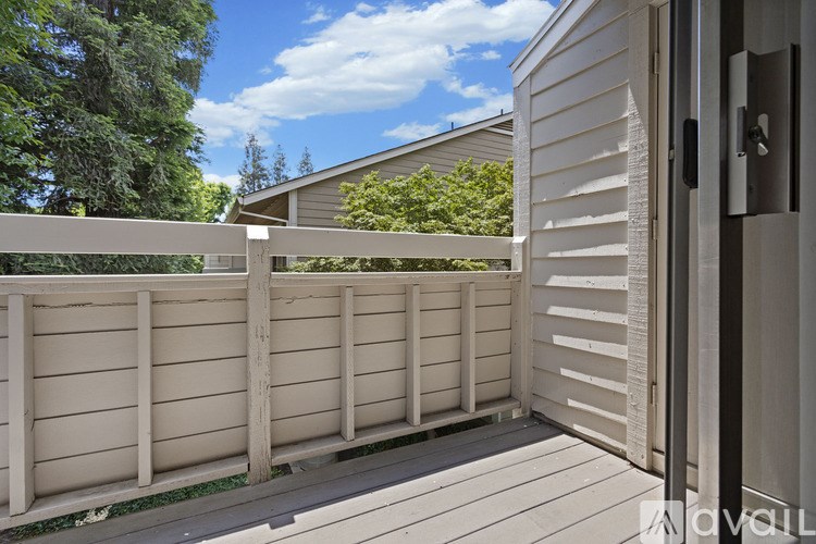 A wooden deck with a white fence and a house in the background.