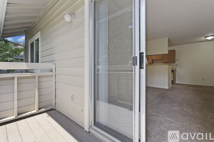 A balcony with a glass door leading to an empty room.